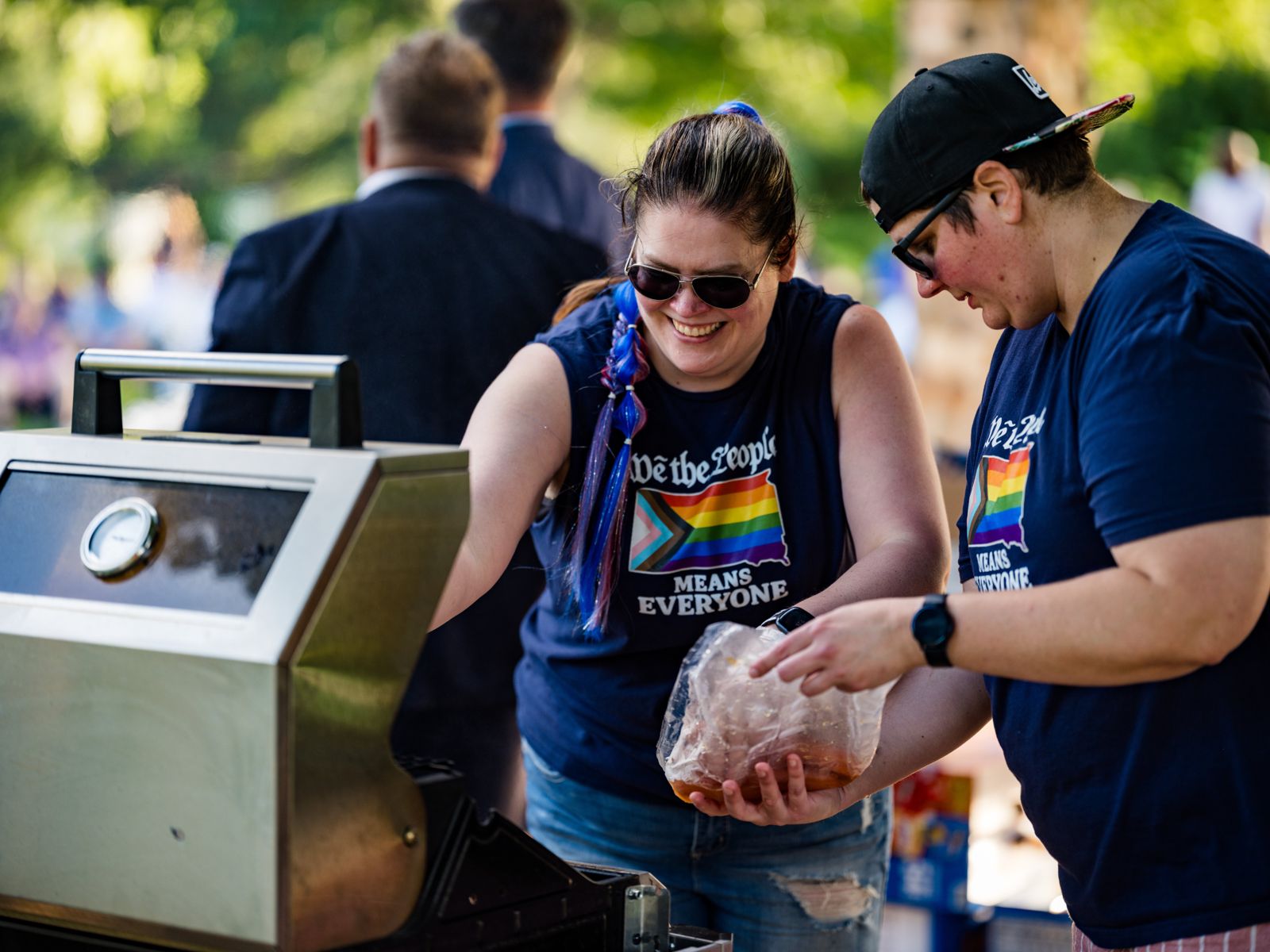 Two volunteers laughing while they fire up the grill at the Dems picnic