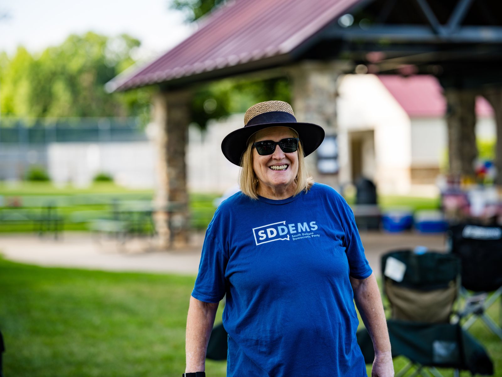A smiling volunteer in a sun hat and South Dakota Democrats T-shirt
